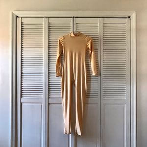 A body suit that appears to be made out of human skin hangs in front of a closet.