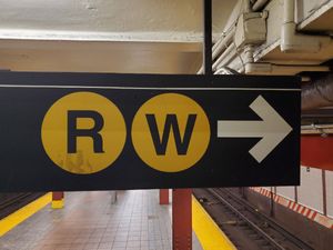 A wayfinding sign for the R and W trains in a New York City subway station