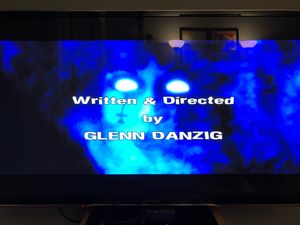 A TV screen displaying the words “Written & Directed by GLENN DANZIG”