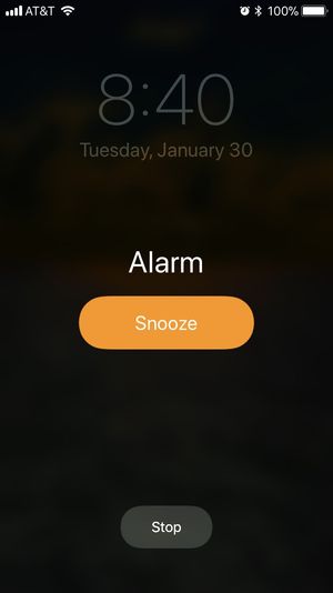 On the iOS lock screen, the Alarm’s primary option is Snooze, secondary option is Stop.