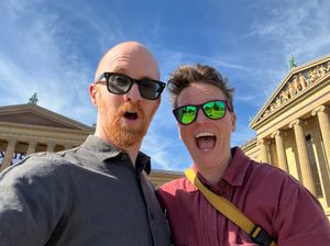 Two smiling people in sunglasses standing in front of the Philadelphia Museum of Art